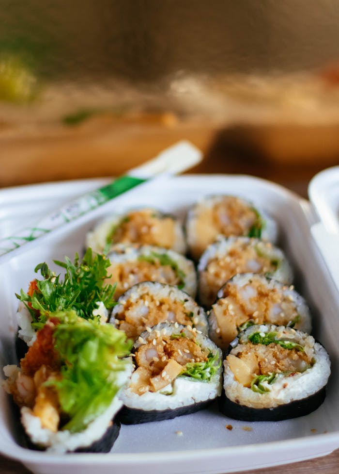 Appetizing sushi rolls in a takeaway box, perfect for a fresh and healthy meal.